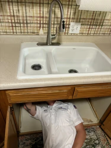 A Royal Plumbing professional fixing a clogged drain